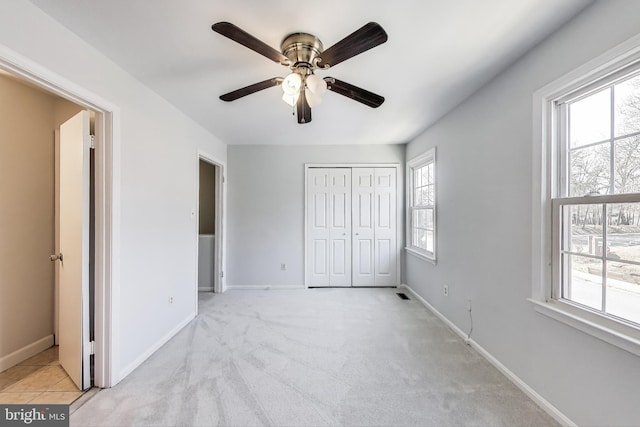 unfurnished bedroom with a closet, baseboards, light carpet, and ceiling fan