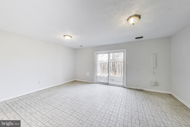 spare room featuring visible vents, baseboards, and a textured ceiling