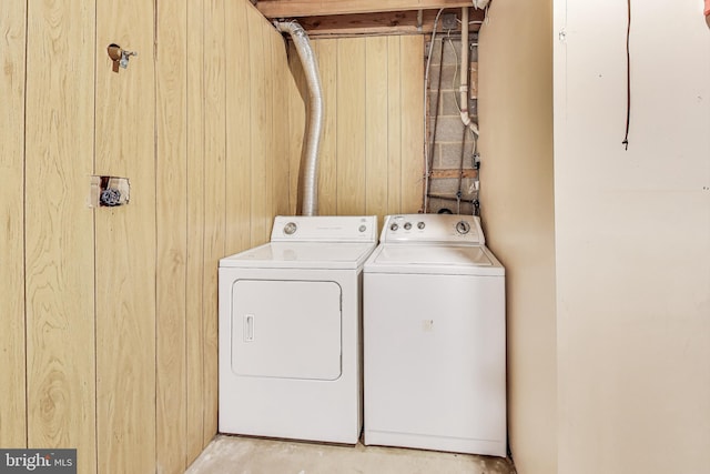 laundry room featuring laundry area, wooden walls, and separate washer and dryer