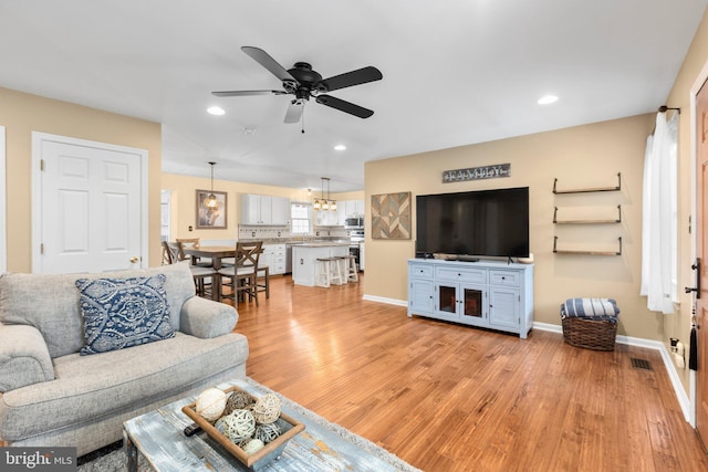 living room featuring a ceiling fan, visible vents, baseboards, recessed lighting, and light wood-style floors