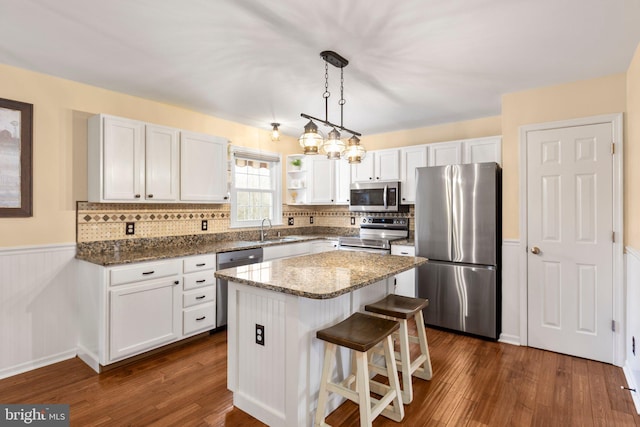 kitchen with a sink, dark stone countertops, dark wood-style flooring, and stainless steel appliances