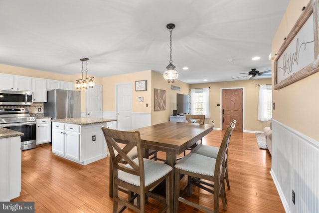 dining room with recessed lighting, a wainscoted wall, a ceiling fan, and light wood finished floors