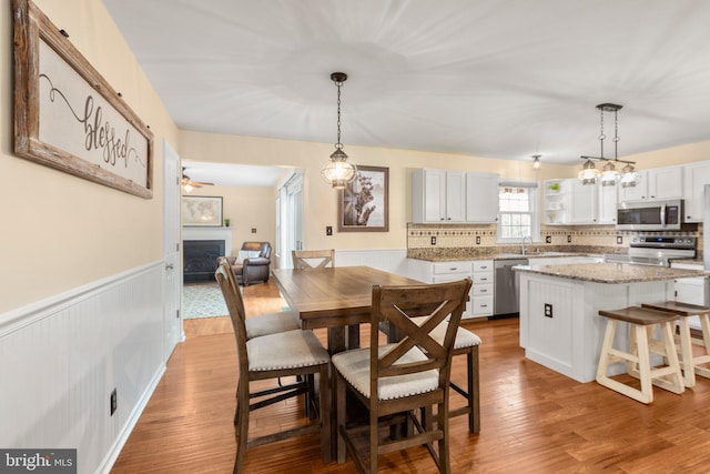 dining area with a wainscoted wall, wood finished floors, and a fireplace