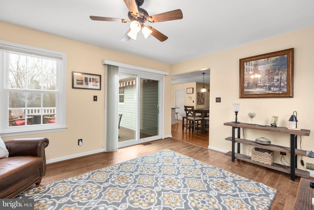 living area featuring baseboards, wood finished floors, and ceiling fan