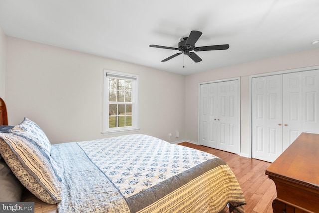 bedroom with a ceiling fan, wood finished floors, multiple closets, and baseboards