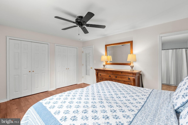 bedroom featuring a ceiling fan, multiple closets, and wood finished floors