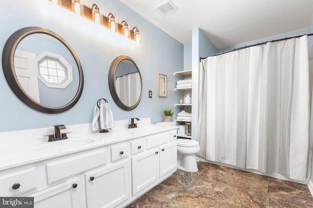 bathroom featuring a sink, visible vents, toilet, and double vanity