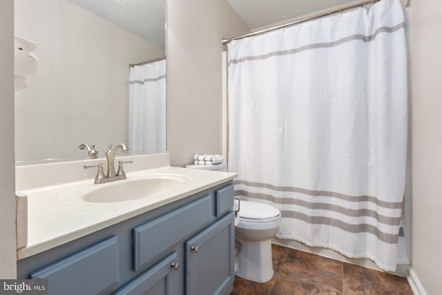 bathroom featuring a shower with shower curtain, stone finish floor, toilet, and vanity