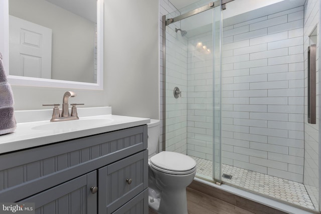 full bathroom with toilet, a stall shower, and vanity