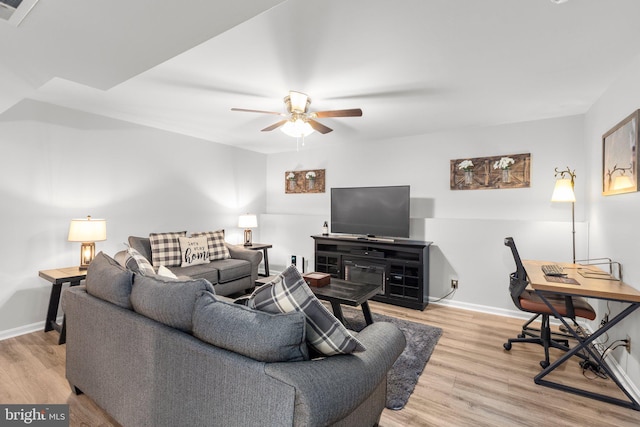 living room with baseboards, wood finished floors, visible vents, and ceiling fan