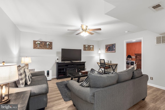 living room with wood finished floors, visible vents, and ceiling fan