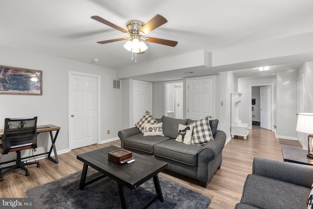 living room with light wood-style flooring, a ceiling fan, visible vents, and baseboards