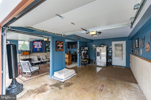 garage featuring a garage door opener and stainless steel refrigerator with ice dispenser