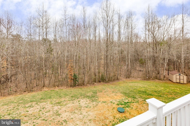 view of yard featuring a forest view, a storage unit, and an outdoor structure