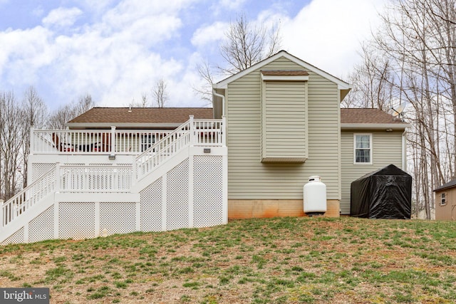 back of house with a yard, roof with shingles, a deck, and stairs