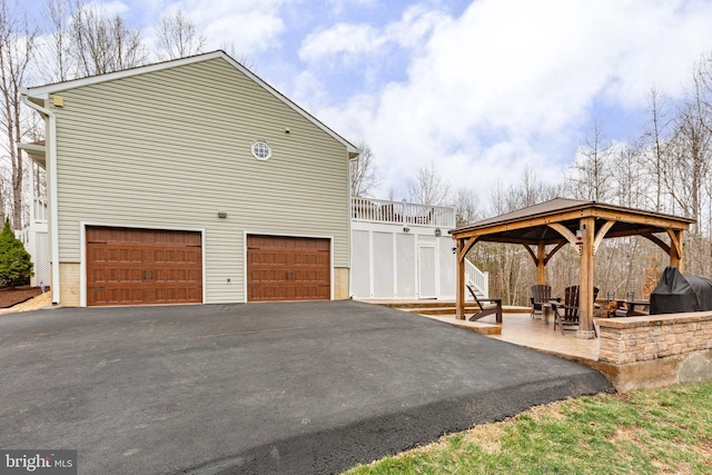 view of side of home featuring a gazebo, an attached garage, and driveway