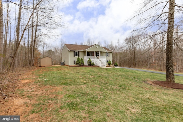 view of front facade with a front yard, an outbuilding, cooling unit, covered porch, and a storage shed