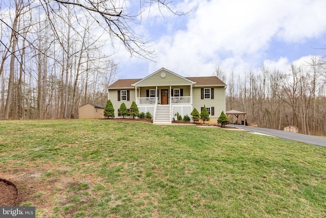 view of front of house with a front lawn, a gazebo, covered porch, an outdoor structure, and driveway