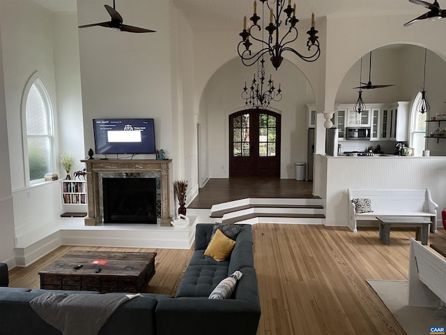 living room with arched walkways, french doors, a ceiling fan, and wood finished floors