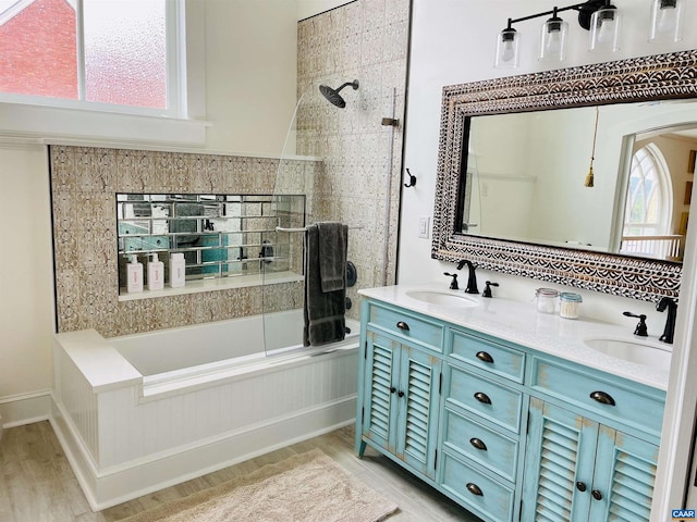 full bathroom featuring double vanity, wood finished floors, tiled shower / bath, and a sink