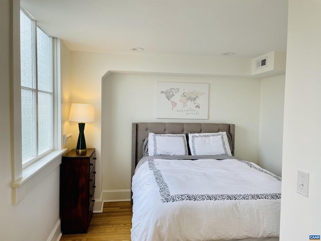 bedroom featuring visible vents, baseboards, and wood finished floors