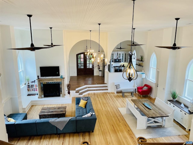 living area with a fireplace with raised hearth, a ceiling fan, and wood finished floors