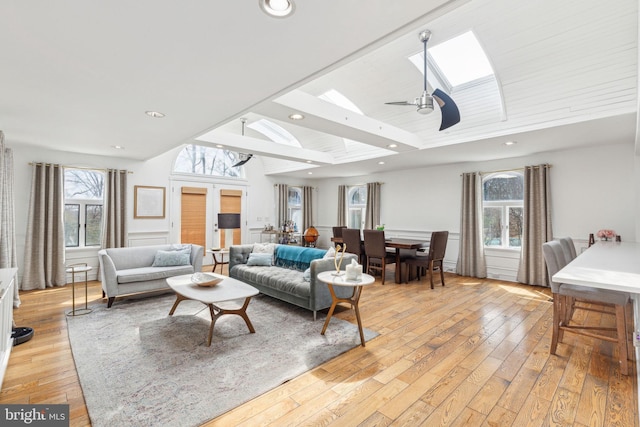 living area with light wood finished floors, vaulted ceiling with skylight, recessed lighting, ceiling fan, and french doors