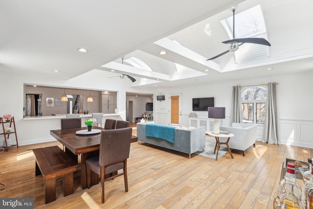 dining space featuring recessed lighting, a skylight, light wood-style floors, a decorative wall, and a ceiling fan