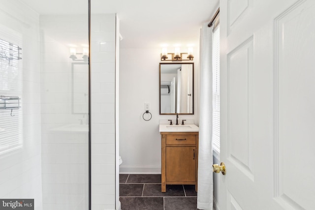 bathroom featuring vanity, toilet, a tile shower, and tile patterned flooring