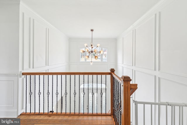 hall with an inviting chandelier, a decorative wall, and wood finished floors