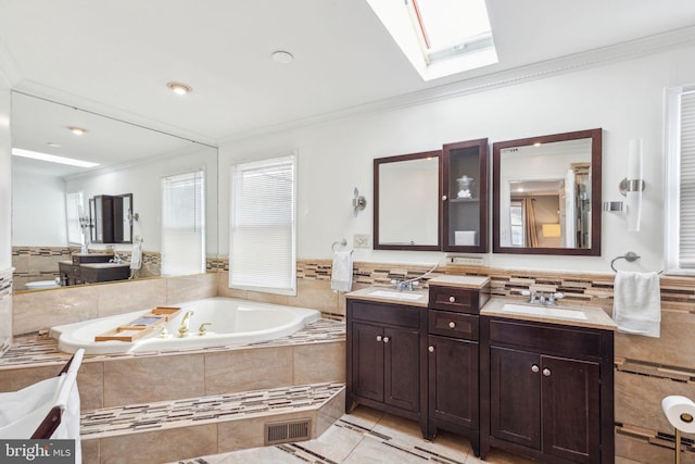 bathroom with crown molding, a skylight, a garden tub, and a sink