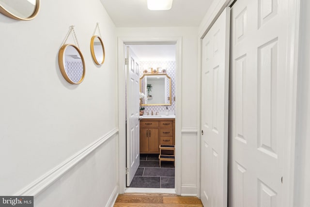 corridor featuring a sink and wood finished floors