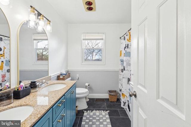 full bath featuring a sink, toilet, a healthy amount of sunlight, and tile patterned floors