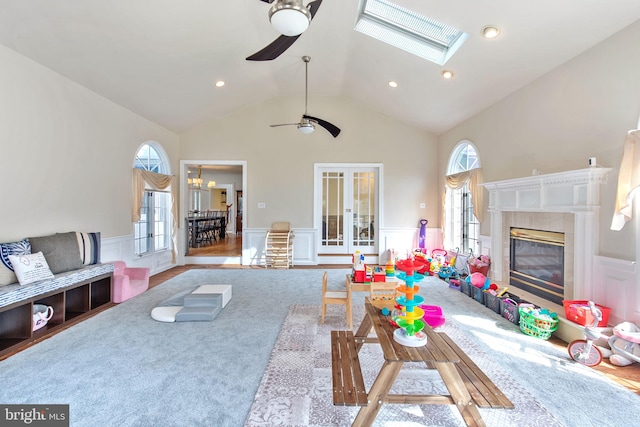 living room with a high end fireplace, wainscoting, lofted ceiling with skylight, and a healthy amount of sunlight