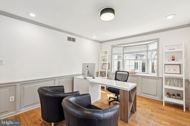 office featuring light wood-type flooring, wainscoting, visible vents, and ornamental molding