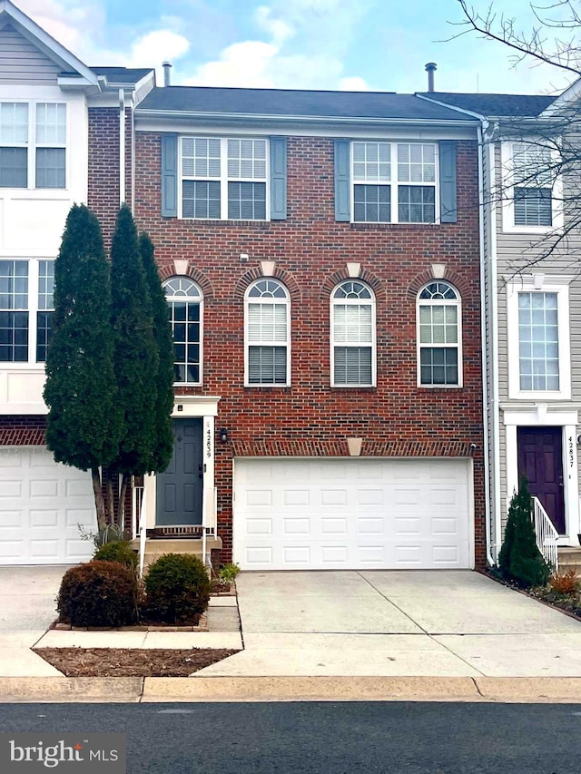 townhome / multi-family property with brick siding, an attached garage, and concrete driveway