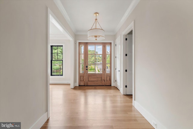 foyer entrance featuring crown molding, light wood-type flooring, and baseboards