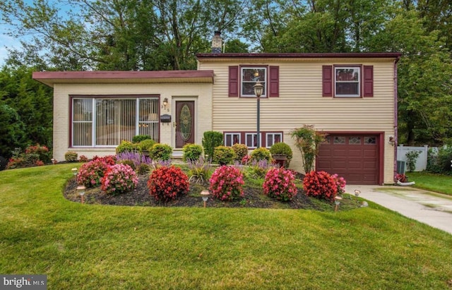 split level home featuring driveway, an attached garage, a chimney, a front lawn, and brick siding