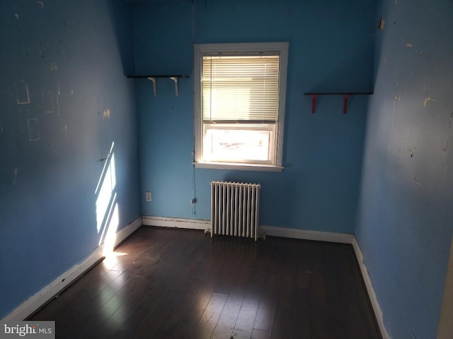 unfurnished room featuring radiator, baseboards, and hardwood / wood-style flooring