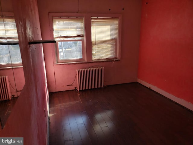 unfurnished room with radiator, radiator heating unit, baseboards, and wood-type flooring