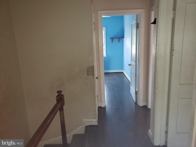 hallway with baseboards, an upstairs landing, and dark wood-style floors