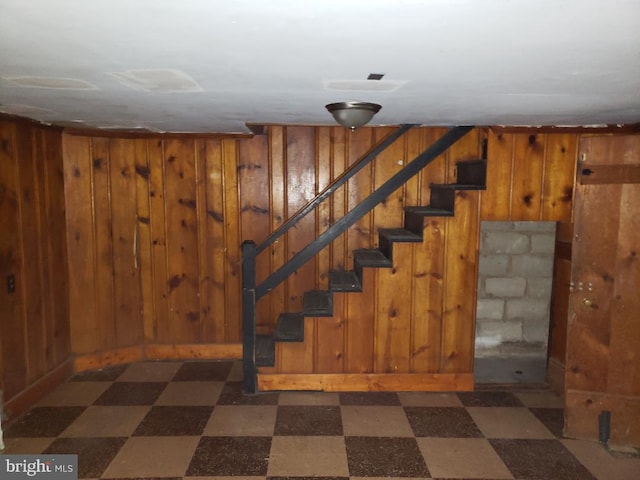 finished basement with wood walls, stairs, and dark floors