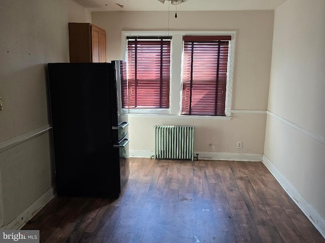 interior space with baseboards, radiator heating unit, and dark wood-type flooring