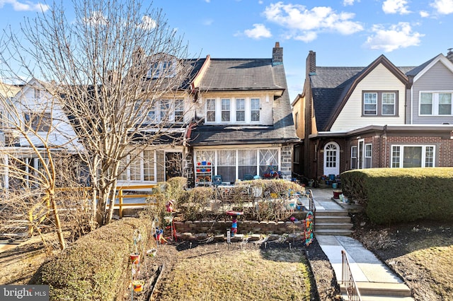 shingle-style home with brick siding and a chimney