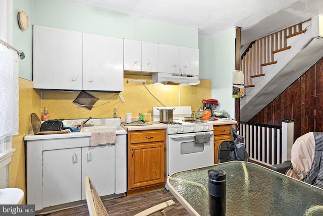 kitchen with under cabinet range hood, light countertops, white gas range oven, decorative backsplash, and wood finished floors