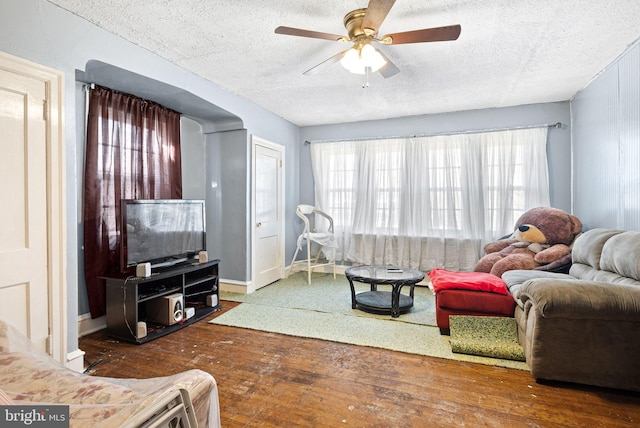 living room with baseboards, a textured ceiling, hardwood / wood-style floors, and a ceiling fan