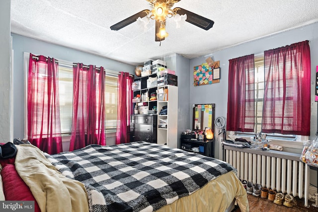 bedroom featuring ceiling fan, multiple windows, radiator, and a textured ceiling