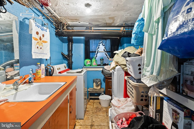 washroom featuring laundry area, washing machine and dryer, concrete block wall, and a sink