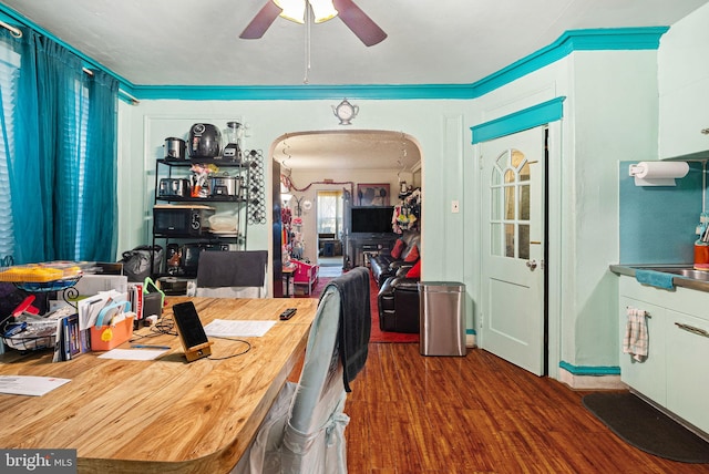 interior space featuring ornamental molding, wood finished floors, arched walkways, and ceiling fan