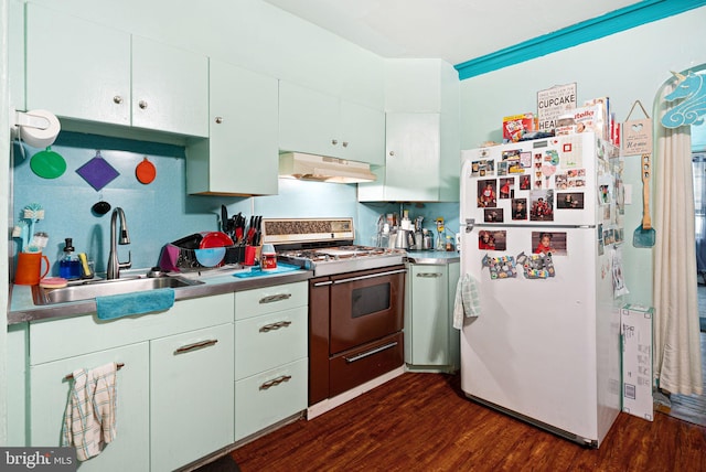 kitchen with under cabinet range hood, a sink, gas range oven, freestanding refrigerator, and dark wood-style flooring